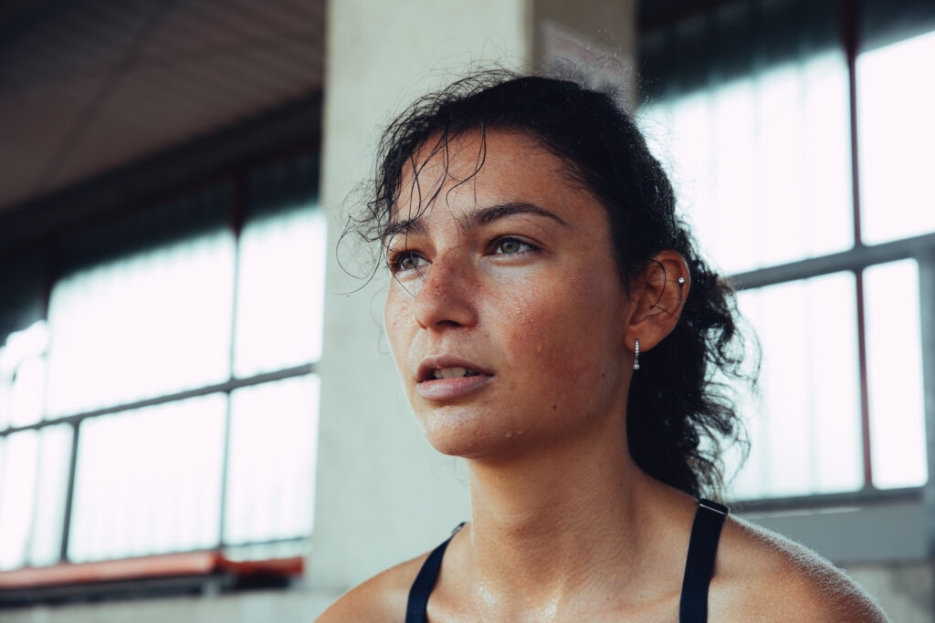 Nahaufnahme der Sportlerin, die erschöpft und verschwitzt in ide Ferne schaut